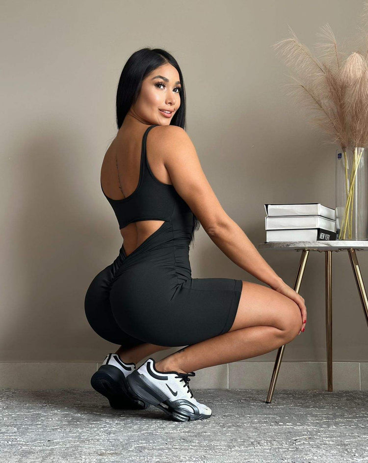 Mujer usando enterizo deportivo biker negro con espalda descubierta y ajuste moldeador en posición agachada