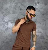 Hombre con camiseta polo texturizada beige de algodón, estilo clásico y moderno, frente a fondo gris