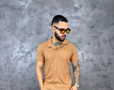 Hombre con camiseta polo texturizada beige de algodón, estilo clásico y moderno, frente a fondo gris