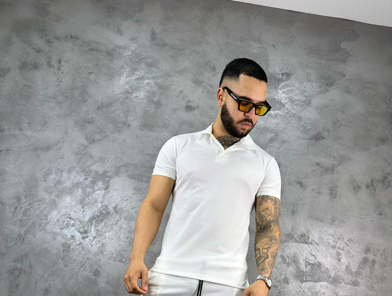 Hombre con camiseta polo texturizada beige de algodón, estilo clásico y moderno, frente a fondo gris