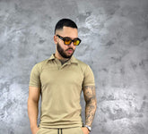 Hombre con camiseta polo texturizada beige de algodón, estilo clásico y moderno, frente a fondo gris