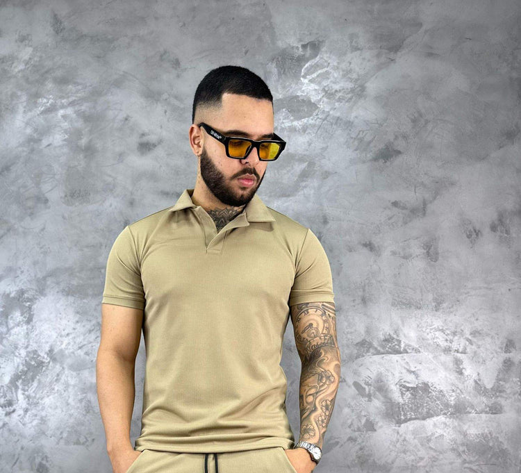 Hombre con camiseta polo texturizada beige de algodón, estilo clásico y moderno, frente a fondo gris