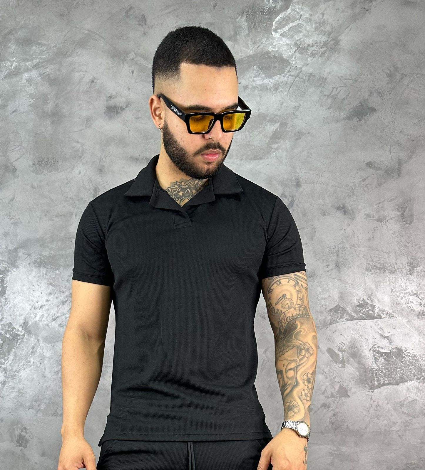 Hombre con camiseta polo texturizada beige de algodón, estilo clásico y moderno, frente a fondo gris