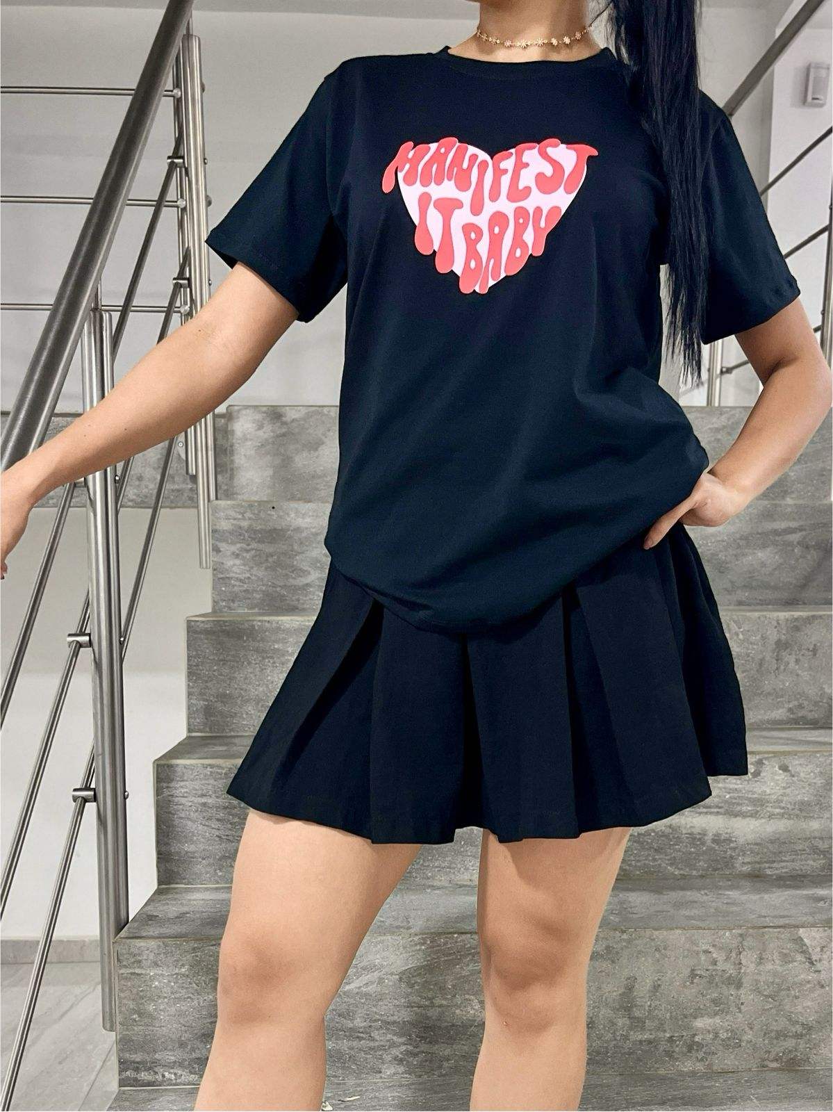 Camiseta de corazones negra con estampado rosa y falda negra en modelo joven.
