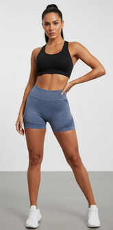 Mujer en ropa deportiva con panty levanta cola azul y top negro, postura segura y estilizada.